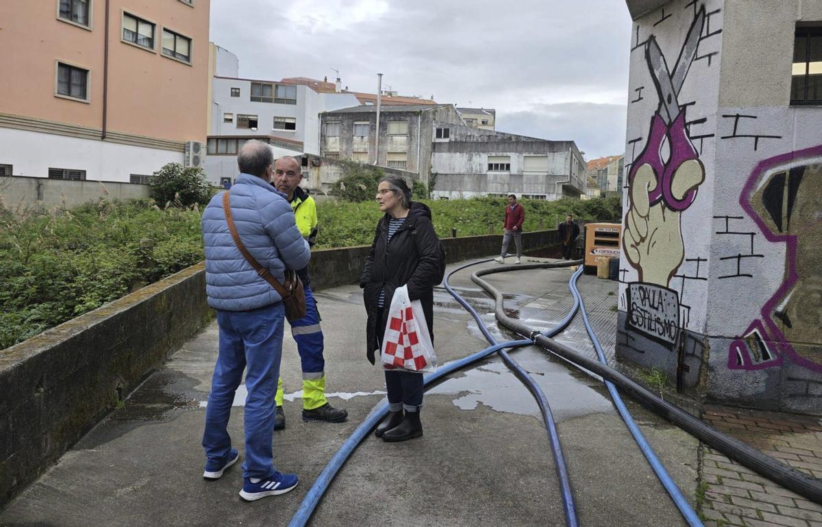 Técnicos del Concello de Cangas, la UTE concesionaria y los vecinos, junto a las mangueras de evacuación. | SANTOS ÁLVAREZ