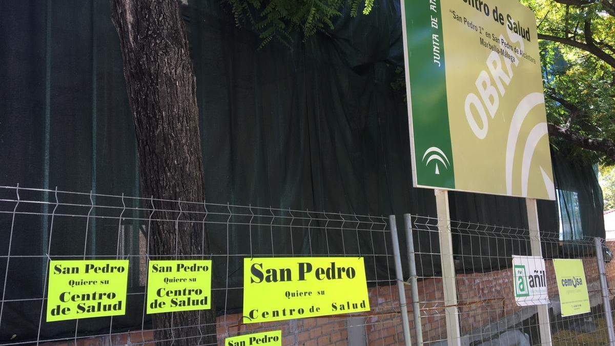 Carteles con la petición de retomar las obras, en la valla que acota el futuro centro de salud.