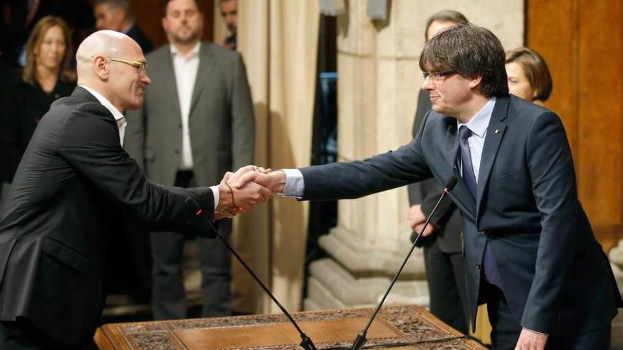 Carles Puigdemont, a la derecha, estrecha la mano de su consejero de Exteriores, Raül Romeva.