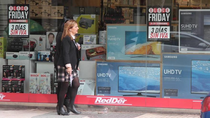 Dos mujeres pasan por delante de un comercio de Cartagena con ofertas de la promoción Black Friday.