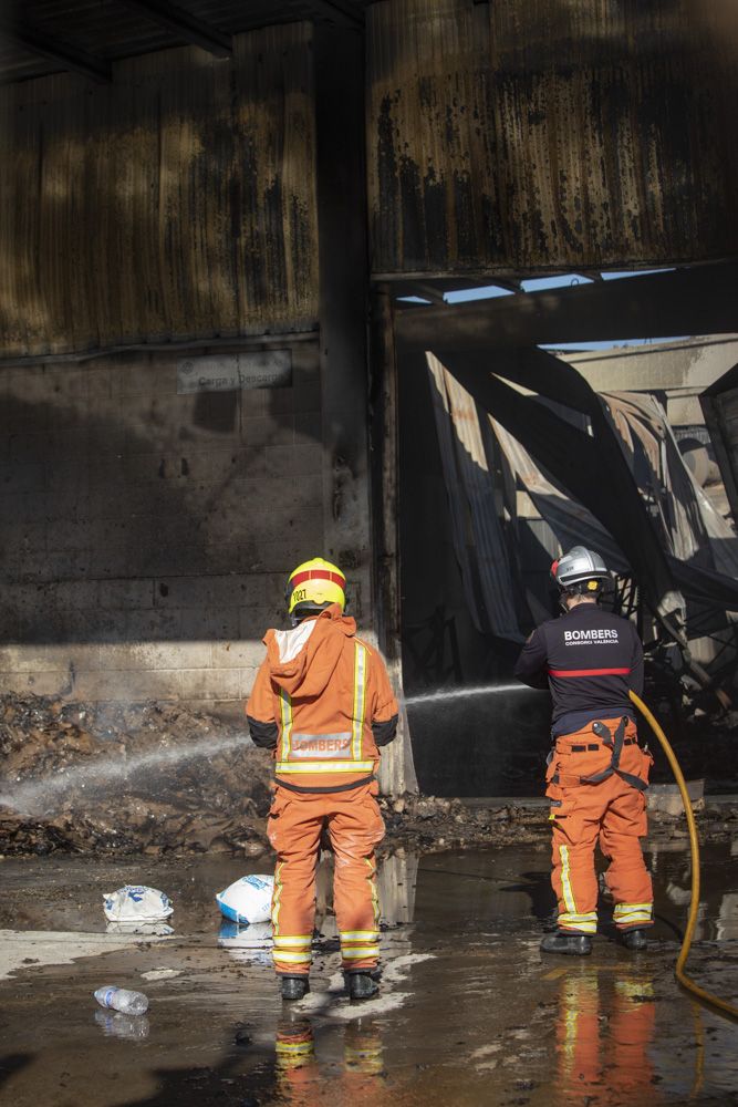 Los bomberos siguen trabajando en la nave del Port de Sagunt un día después del incendio