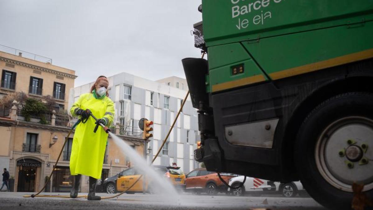 Una trabajadora del servicio de limpieza viaria de Barcelona baldea los entornos de la plaza de Pla de Palau.