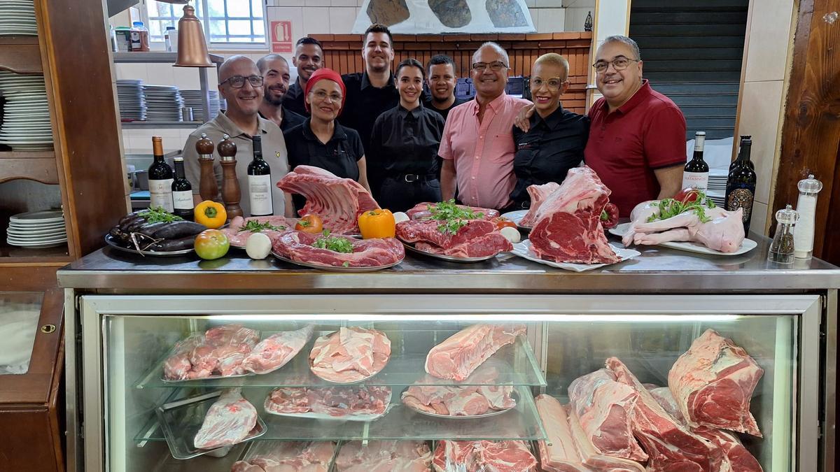 El equipo al completo del restaurante Sal y Brasas de Juan Grande, detrás del expositor donde muestran sus carnes frescas para elección del comensal.