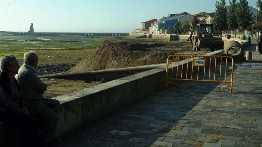 Una pala extiende la arena depositada por los camiones en la zona del paseo marítimo de San Tomé. // Iñaki Abella