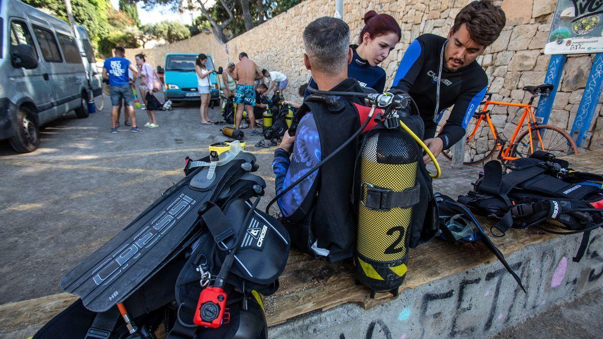 Un instructor prepara el equipo a un buceador novato.