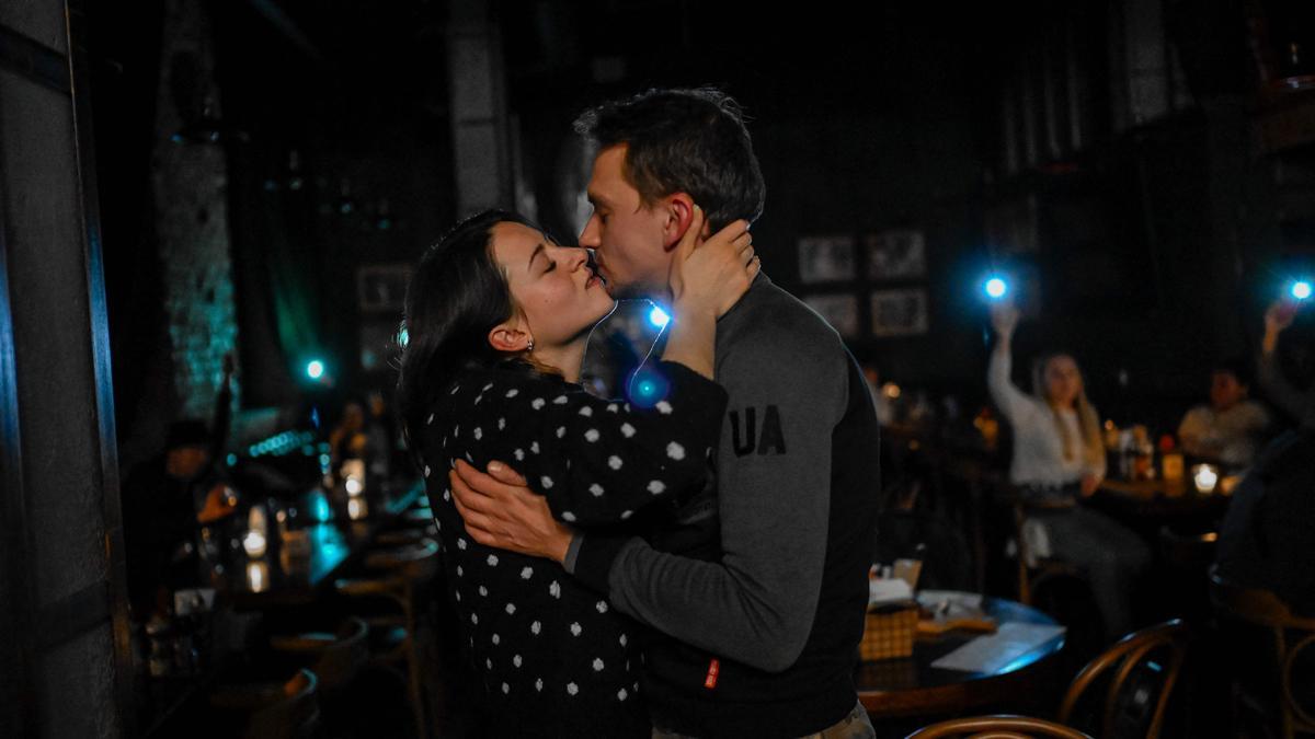 Una pareja se besa en un bar de Kiev, mientras los clientes del bar les alumbran con la luz de sus móviles, durante un corte de electricidad en la ciudad