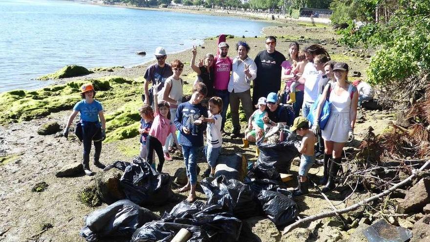 Parte de las familias participantes en la limpieza de la ría, ayer en O Burgo a la altura de la urbanización O Paraíso de Oleiros, con parte de los residuos.