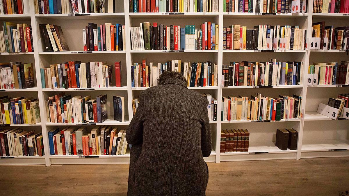 Un lector mira los libros en las estanterías de una librería en Alicante
