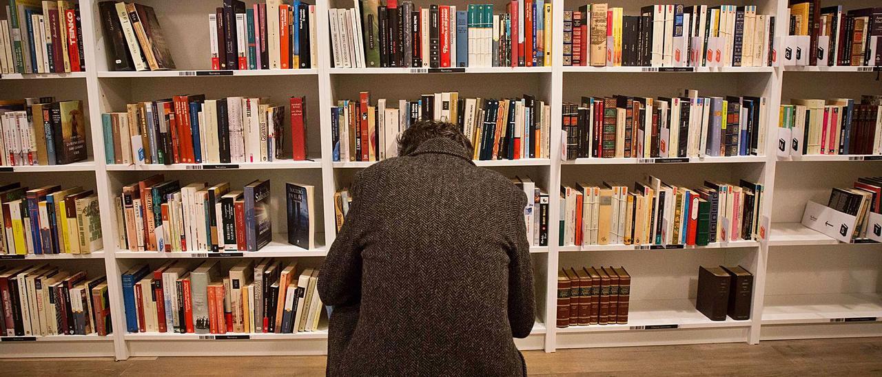 Un lector mira los libros en las estanterías de una librería en Alicante. |