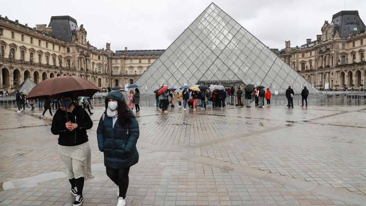 Dos personas se alejan de la principal entrada del Louvre, ayerl