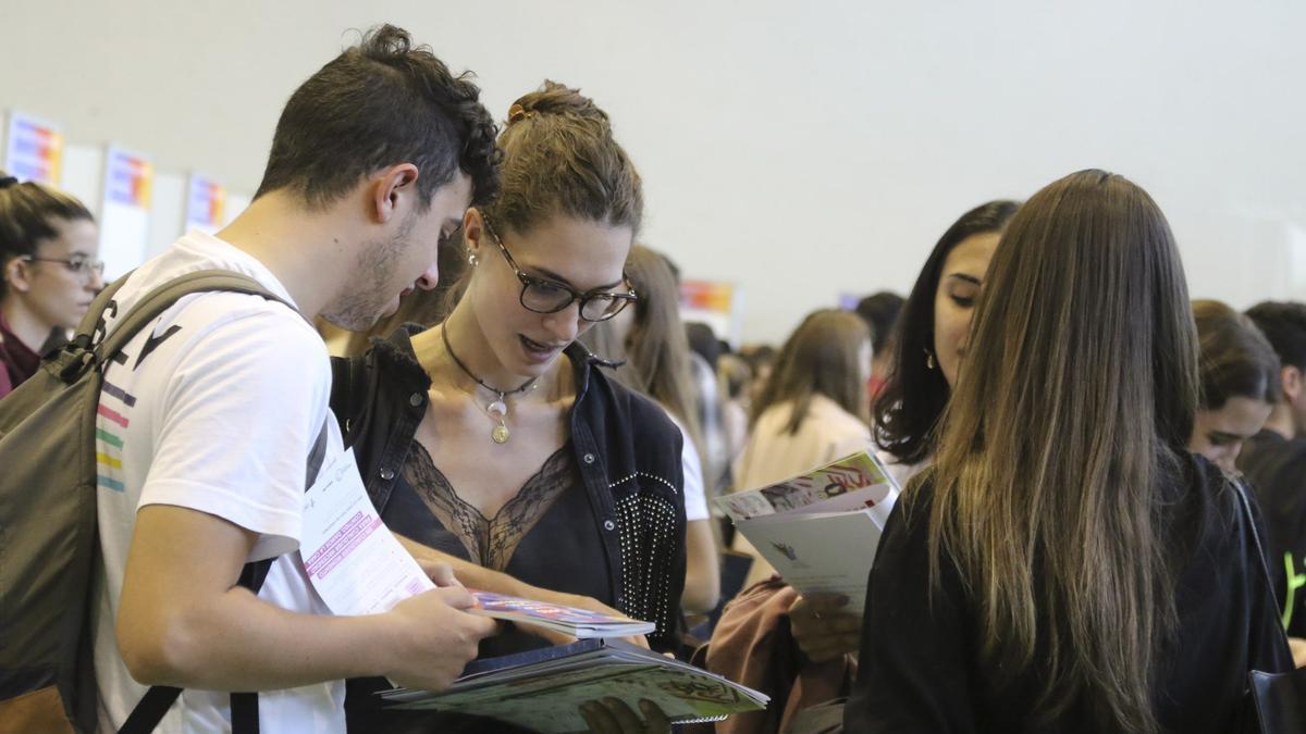 Varios estudiante miran folletos de la Universidad de Salamanca.