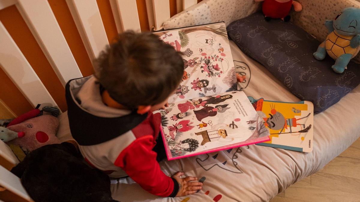 Una niña de 3 años ojea libros infantiles.
