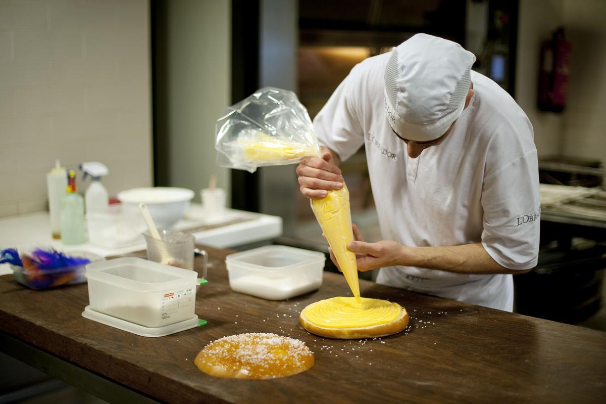 Un pastelero rellena la mona de Pascua de brioche con crema.
