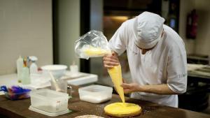 Un pastisser emplena la mona de Pasqua de brioix amb crema.