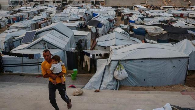 Un home porta un nadó, entre tendes de campanya a Khan Yunis, ahir. | BASHAR TALEB / AFP