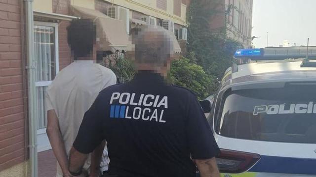 Un Policía Local de San Javier junto conduce al detenido a un coche patrulla.