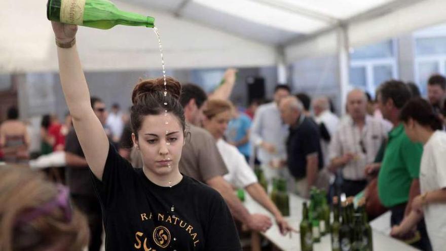 La representante de un lagar escancia una botella en la última Feira da Sidra. // Bernabé/Luismy