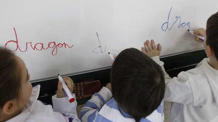 Varios niños escriben en la pizarra de su clase.