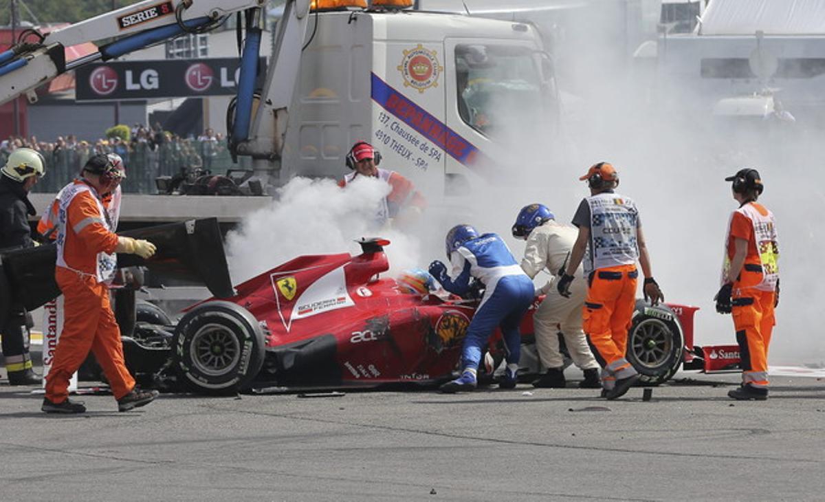 Técnicos del circuito atienden a Fernando Alonso después del choque múltiple.