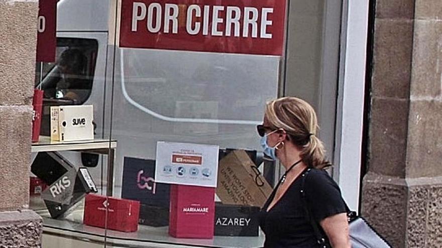 Una mujer mira el escaparate de un comercio en liquidación en Santa Cruz.