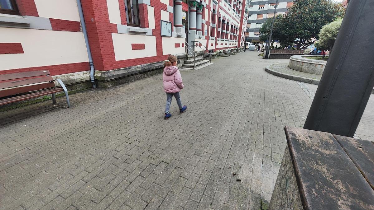 Una niña camina ante la entrada del colegio Aniceto Sela tras pasar al lado de un excremento canino.