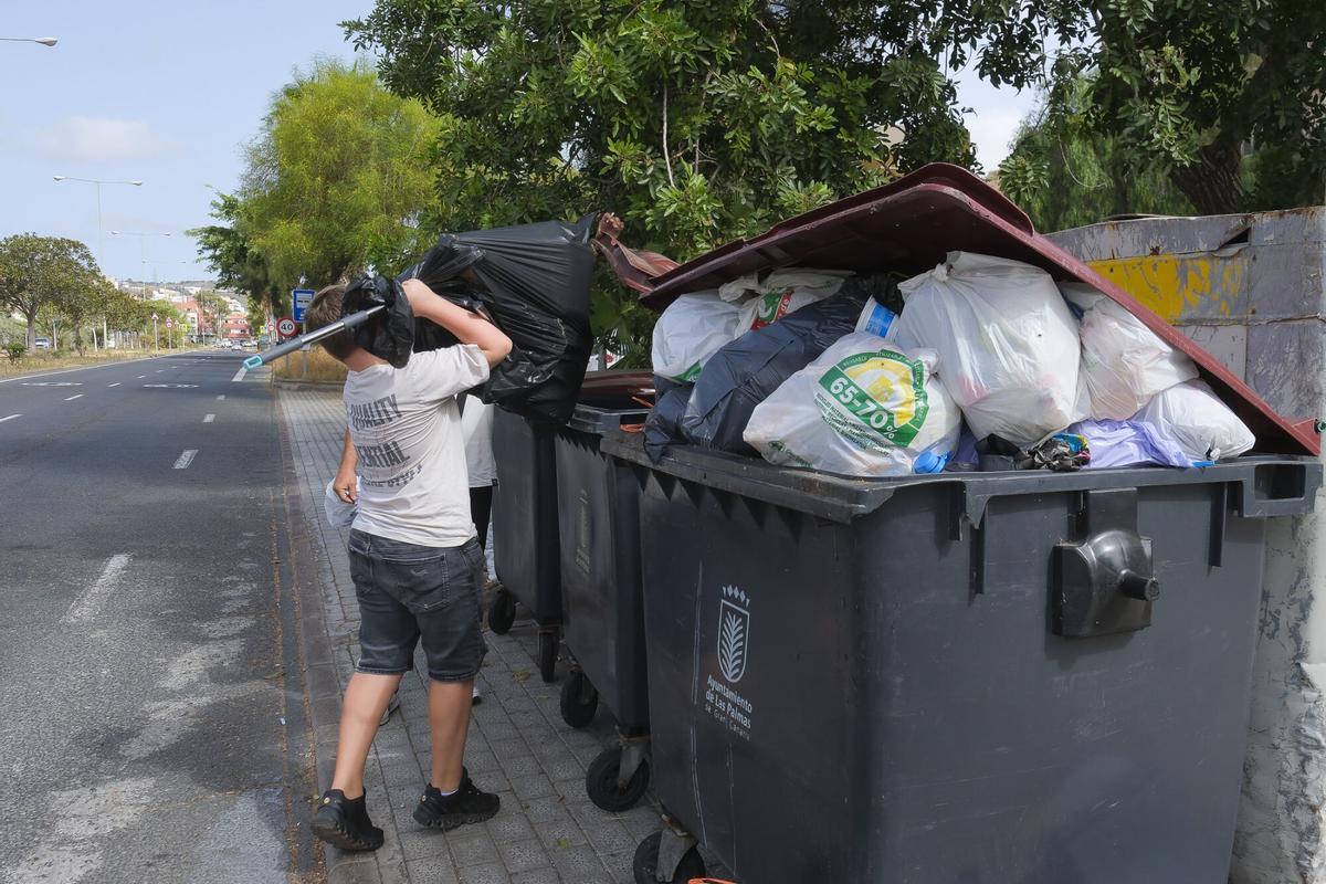 Gente tirando basura en los contenedores.