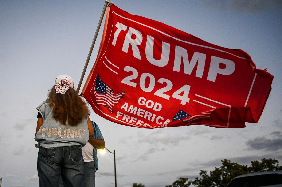 Una partidaria del expresidente estadounidense Donald Trump sostiene una bandera de Trump 2024 mientras protesta cerca del Mar-a-Lago Club en Palm Beach, Florida.