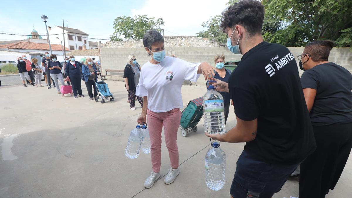 Los vecinos hacen cola esta mañana para recoger garrafas de agua embotellada.