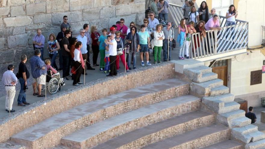 Un grupo de turistas divisa el Teatro Romano desde lo alto del graderío.