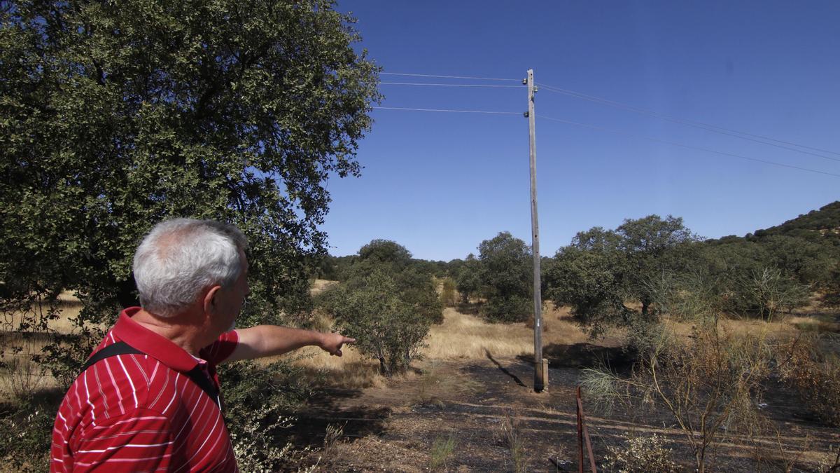 Un vecino señala un poste de luz afectado por el fuego en el incendio de Villaharta.