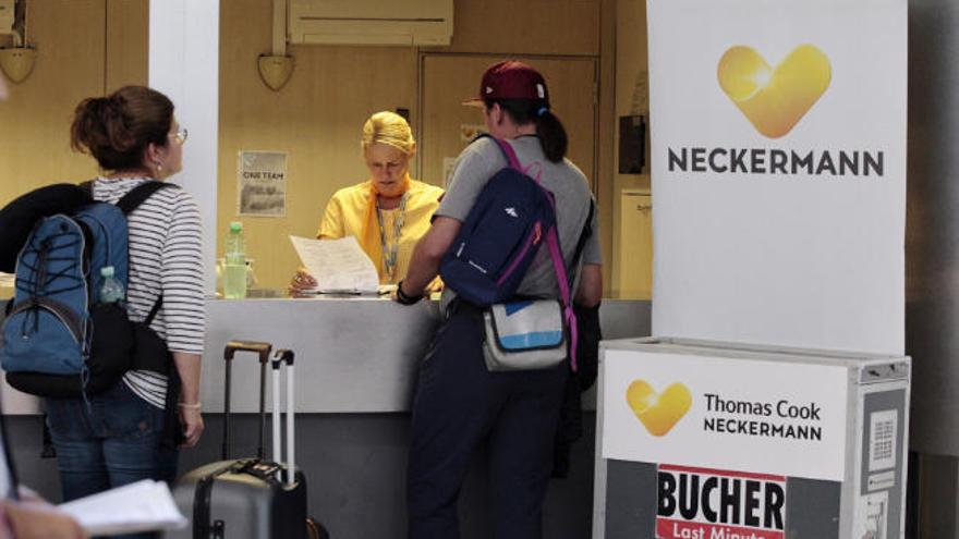 Una empleada de Thomas Cook Neckermann atiende a dos afectadas en el aeropuerto de Tenerife Sur.