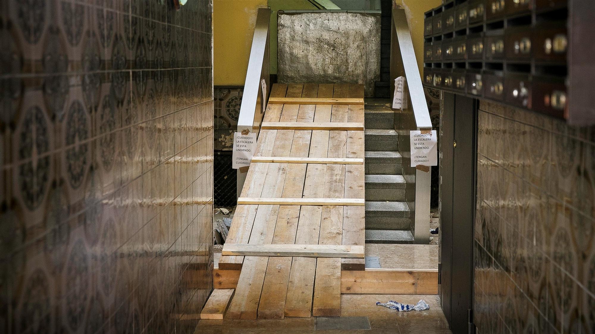 La escalera el bloque de L'Hospitalet del pasaje Oliveras donde se produjo el hundimiento, ahora tapada con unas tablas de madera.