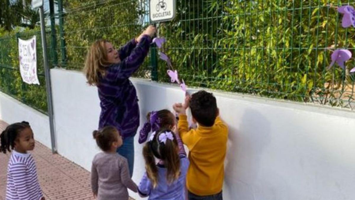 Una maestra ayuda a los niños a colgar su manualidad.