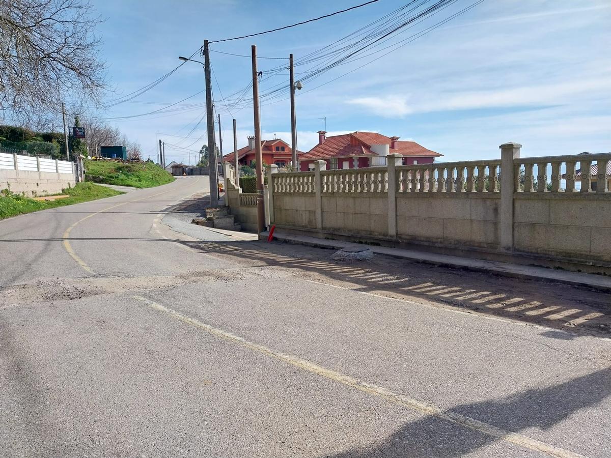 El vial de A Madalena-Herbello a su paso por el lugar de Castelo, con el pozo de drenaje al lado del muro de cierre de una vivienda.