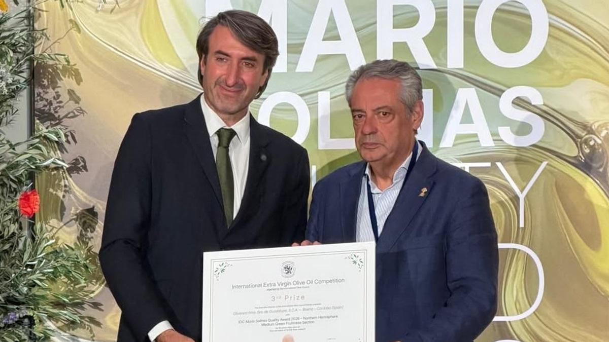 El presidente de la cooperativa Nuestra Señora de Guadalupe de Baena, Javier Alcalá de la Moneda (derecha), recoge el premio.