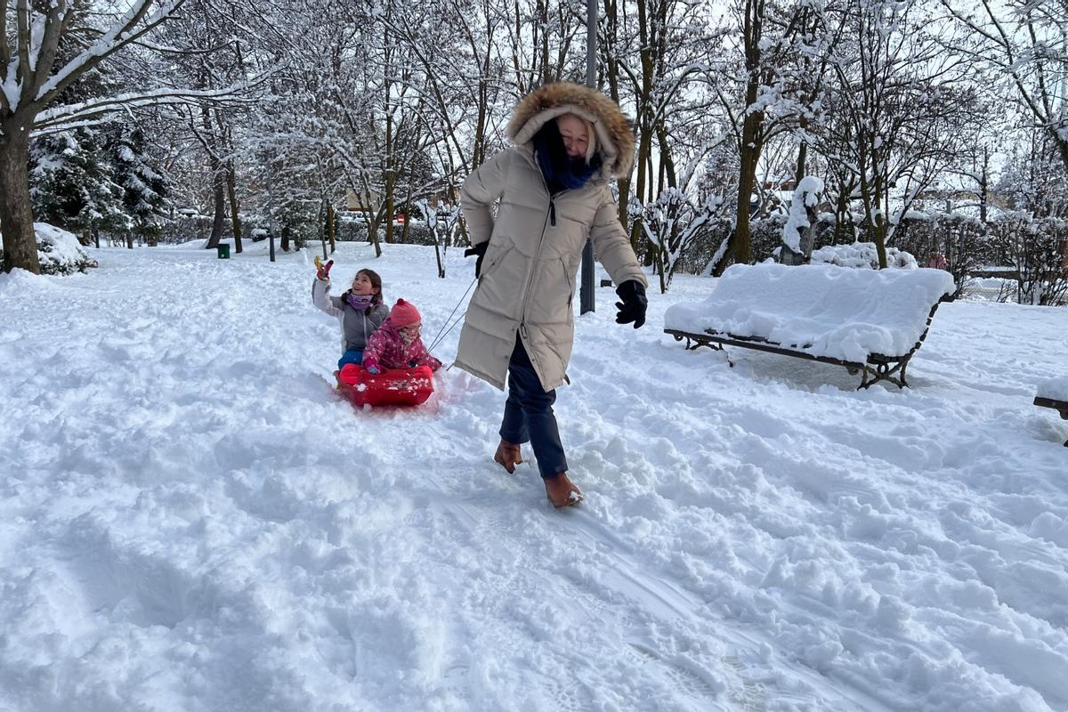 Una família gaudint de la neu amb un trineu al costat de l'estany de Puigcerdà