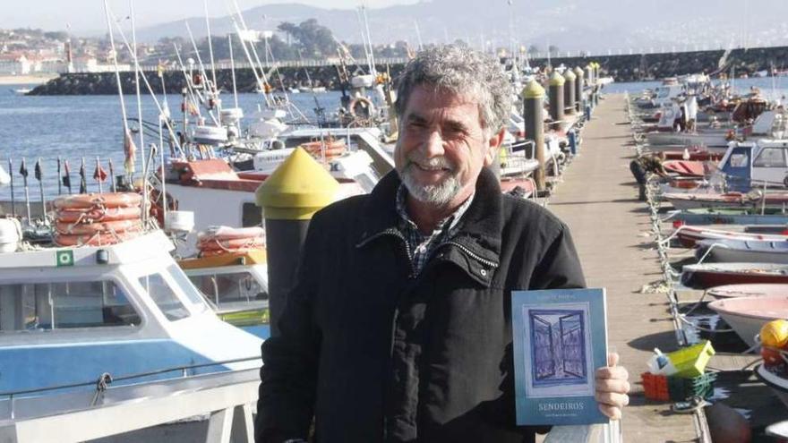 El escritor Luis Chapela sujeta un ejemplar de &quot;Sendeiros&quot;, ayer en el puerto pesquero. // Santos Álvarez