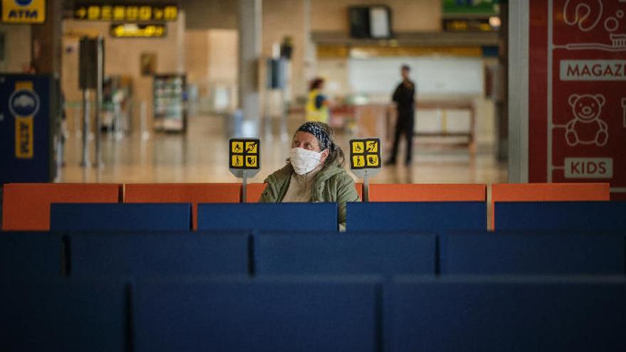 Una mujer, ataviada con mascarilla, sola en los asientos del aeropuerto de Los Rodeos durante el estado de alarma.