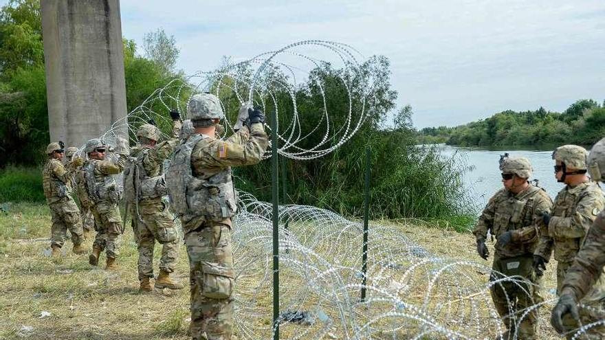 concertinas. Soldados desplegados en Hidalgo (Texas) instalan vallas de alambre con cuchillas para recibir a la caravana de miles de inmigrantes que desde México se dirige a la frontera con EE UU. afp