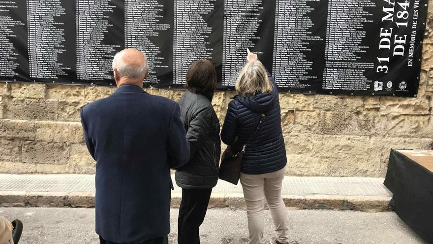Personas que acudieron al viacrucis observando la lona con los nombres de las personas fallecidas por la tragedia.