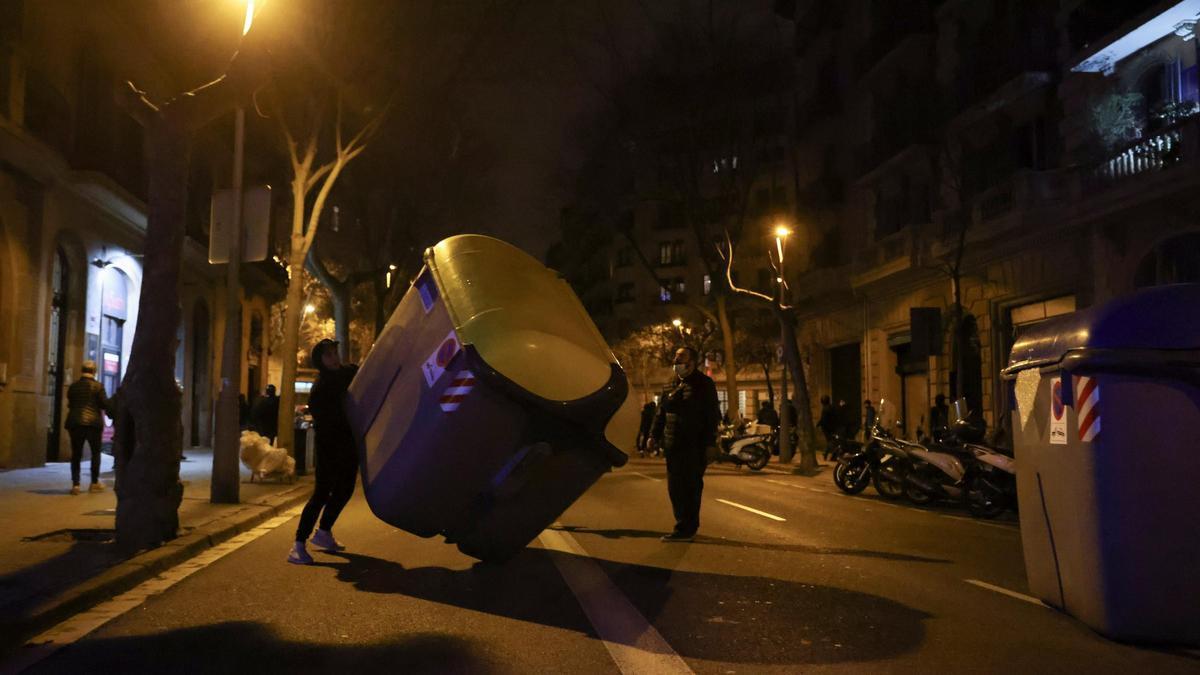 Manifestantes mueven un contenedor en una calle de Barcelona.