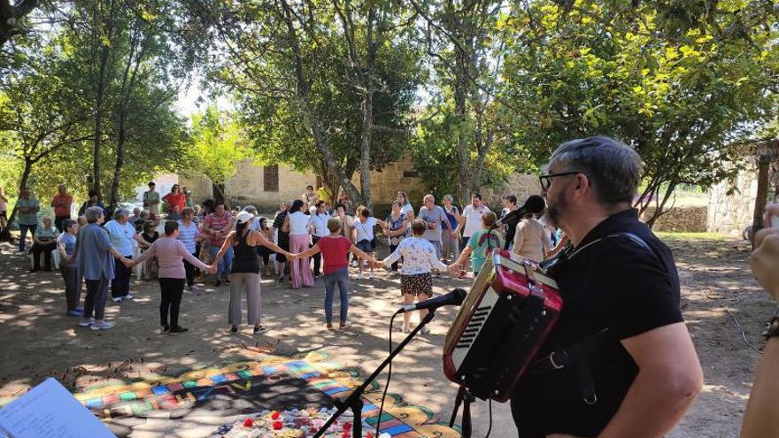 Xavier Blanco tocando el acordeón mientras varios mayores bailan ante la alfombra floral confeccionada para la ocasión.   | GONZALO NÚÑEZ