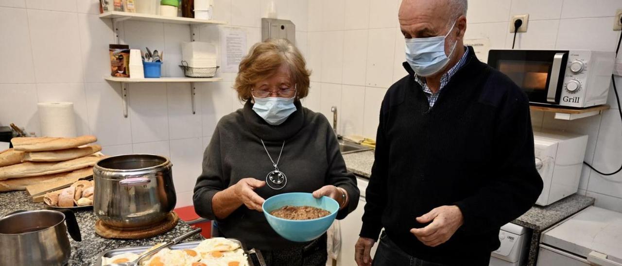 Víctor Rey con una de las voluntarias prepara la cena para los usuarios. // RAFA VÁZQUEZ