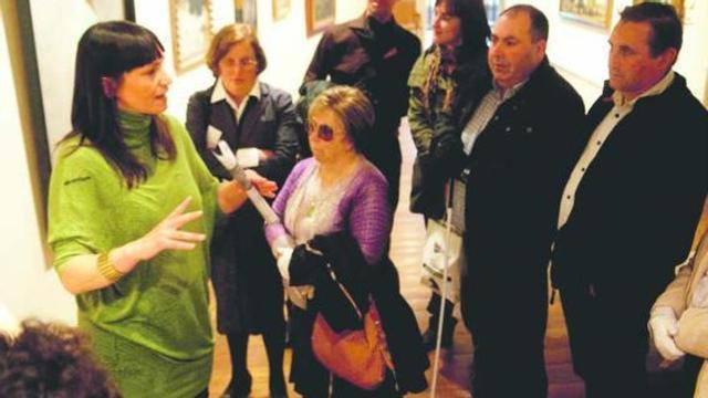 Montserrat Briansó, explicando a un grupo de discapacitados visuales uno de los cuadros.