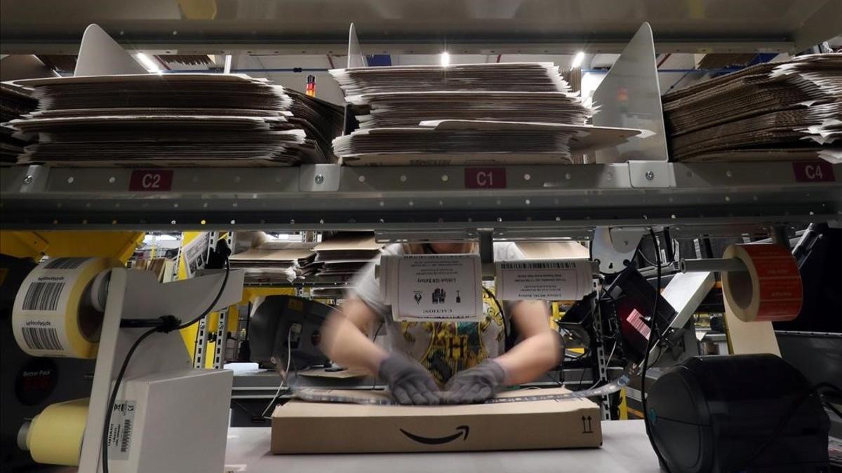 Un trabajador prepara un pedido en una caja de Amazon.