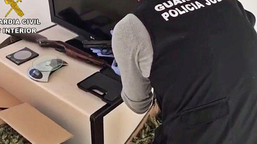 Un guardia civil examina una de las armas intervenidas a uno de los sospechosos.