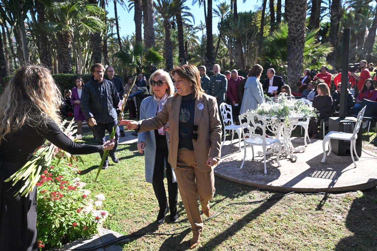 La concejala Caridad Martínez coge una de las flores para depositar en las tumbas