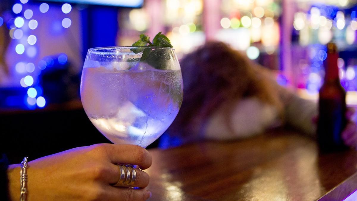 Una mujer sosteniendo una bebida alcohólica en un bar.