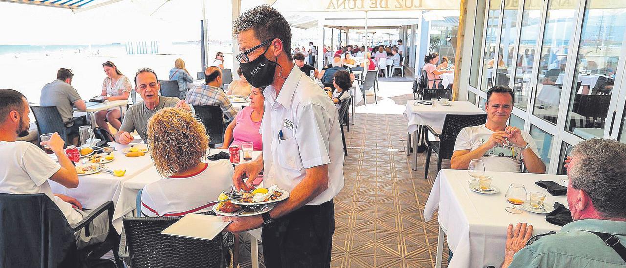 Un camarero sirve unas mesas en la terraza de un restaurante.