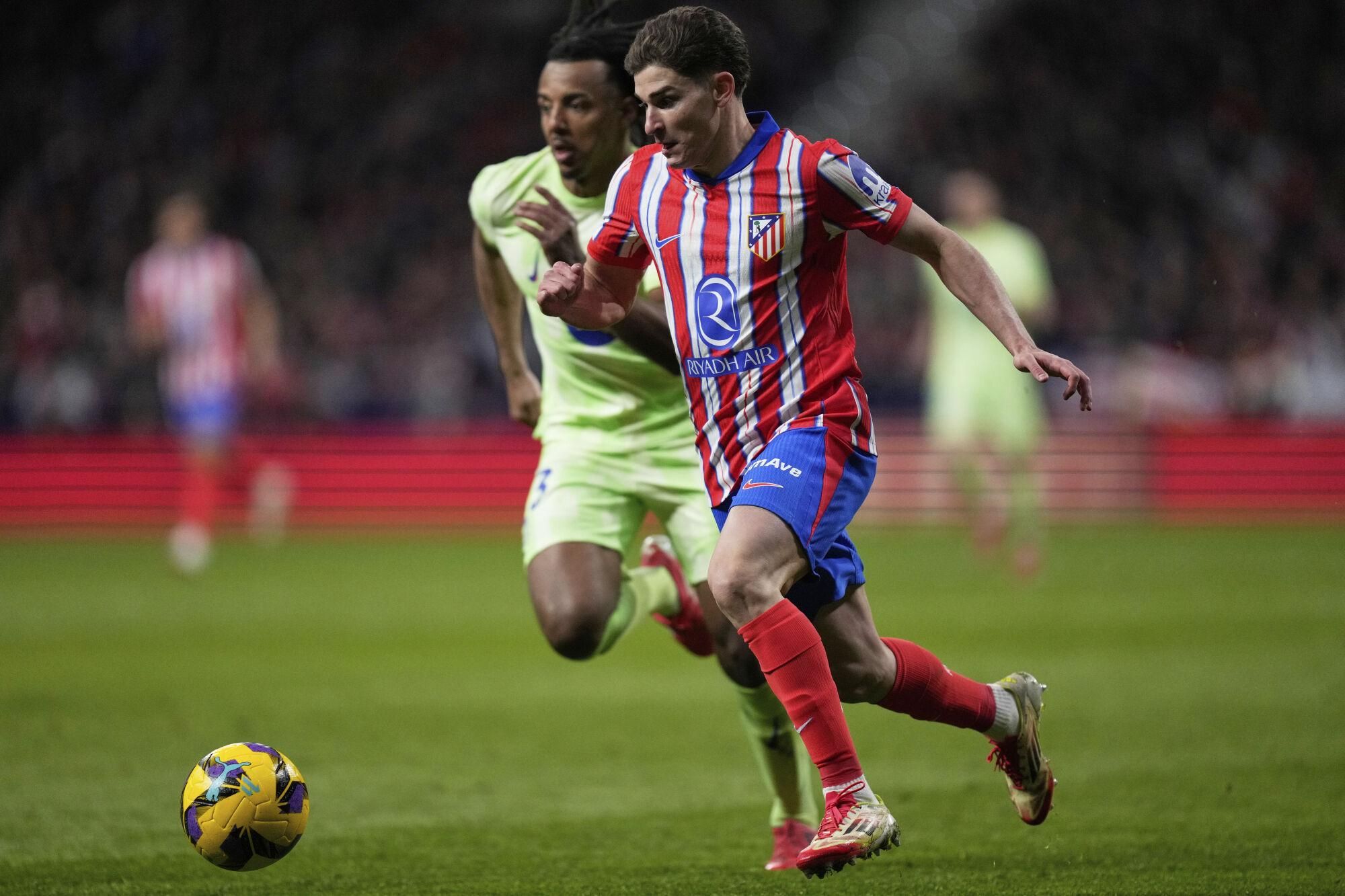 Atletico Madrid's Julian Alvarez, front, and Barcelona's Alejandro Balde compete for the ball during a La Liga soccer match between Atletico Madrid and FC Barcelona at the Metropolitano stadium in Madrid, Sunday, March 16, 2025. (AP Photo/Bernat Armangue)